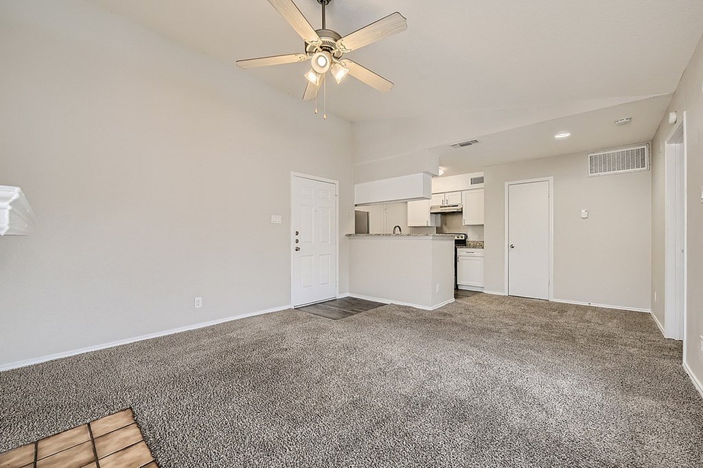 A spacious room with a ceiling fan and carpeted floor.