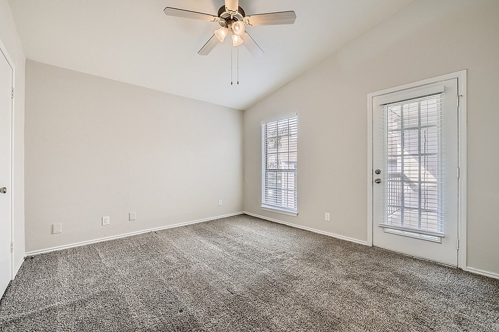 A room with a ceiling fan and carpeted floor.