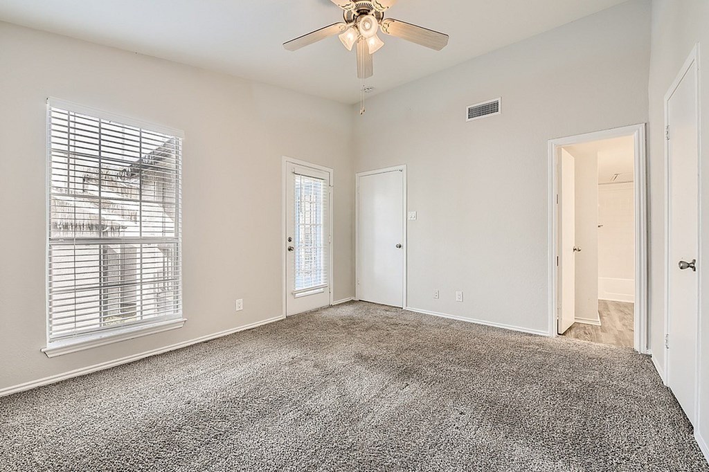 A room with a carpeted floor and a ceiling fan.