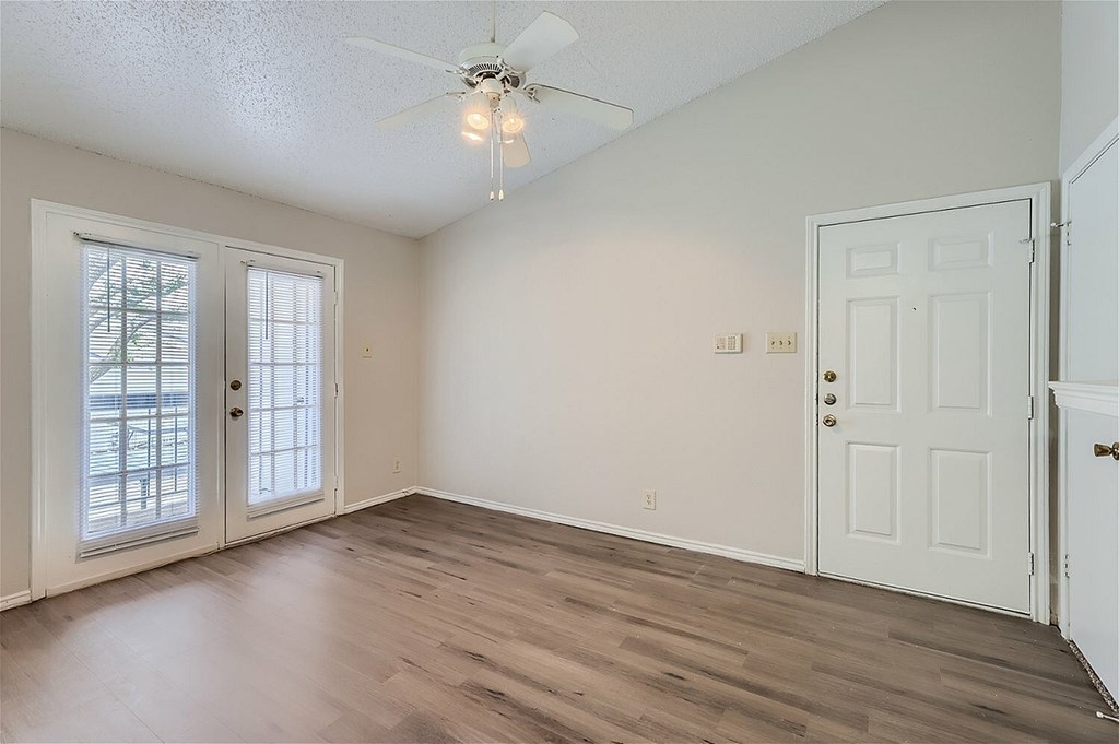 A room with a ceiling fan and wooden flooring.