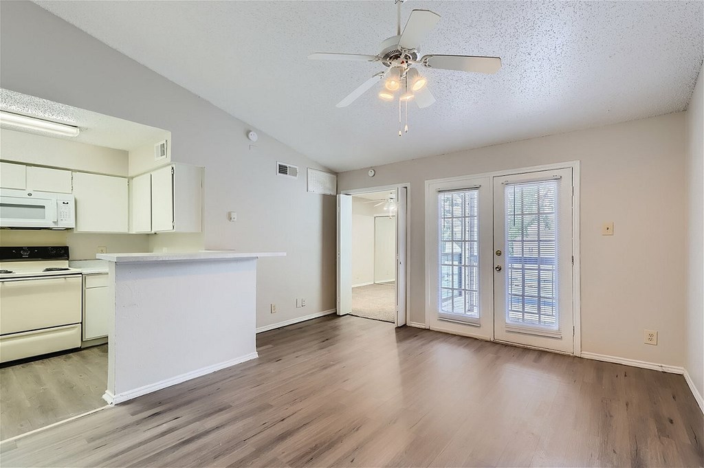 A spacious kitchen and living room with wood flooring and white walls.
