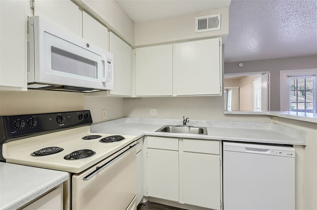 A white kitchen with a stove, microwave, and dishwasher.