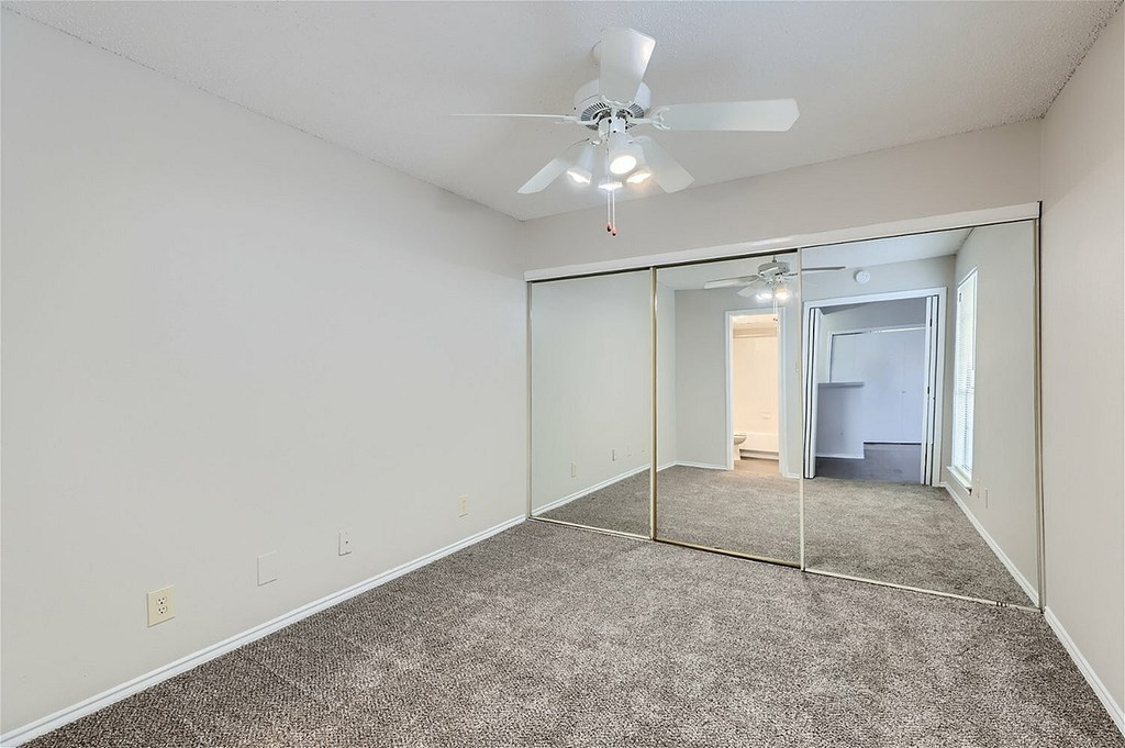 A room with a ceiling fan and a mirror on the wall.