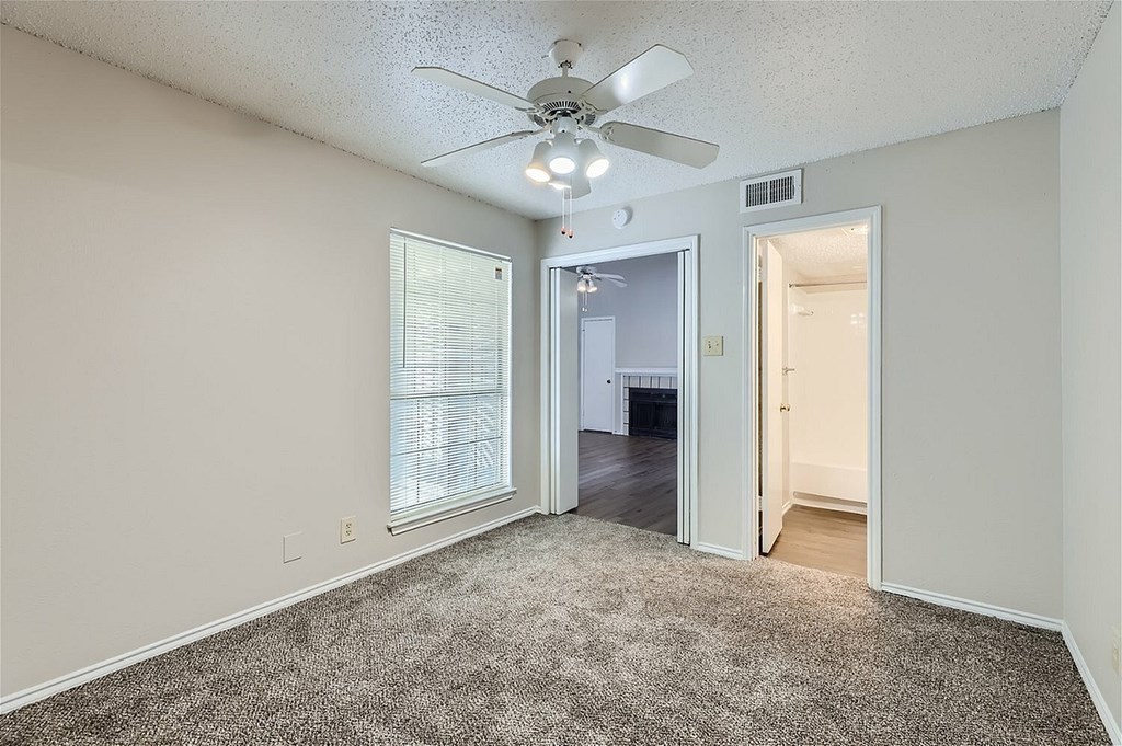 A room with a ceiling fan and carpeted floor.