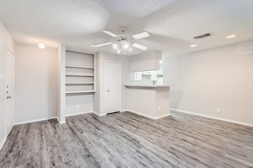 A room with a ceiling fan and grey flooring.