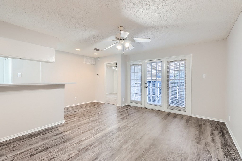 A room with a ceiling fan and a large window.