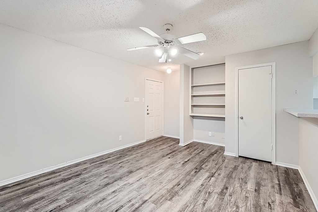 A room with a ceiling fan and wooden flooring.