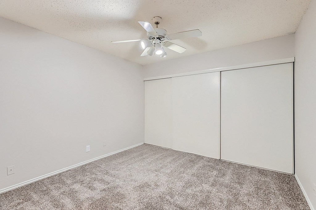 A room with a ceiling fan and carpeted floor.
