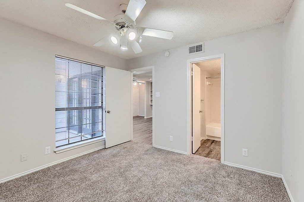 A spacious room with a ceiling fan and a large window.