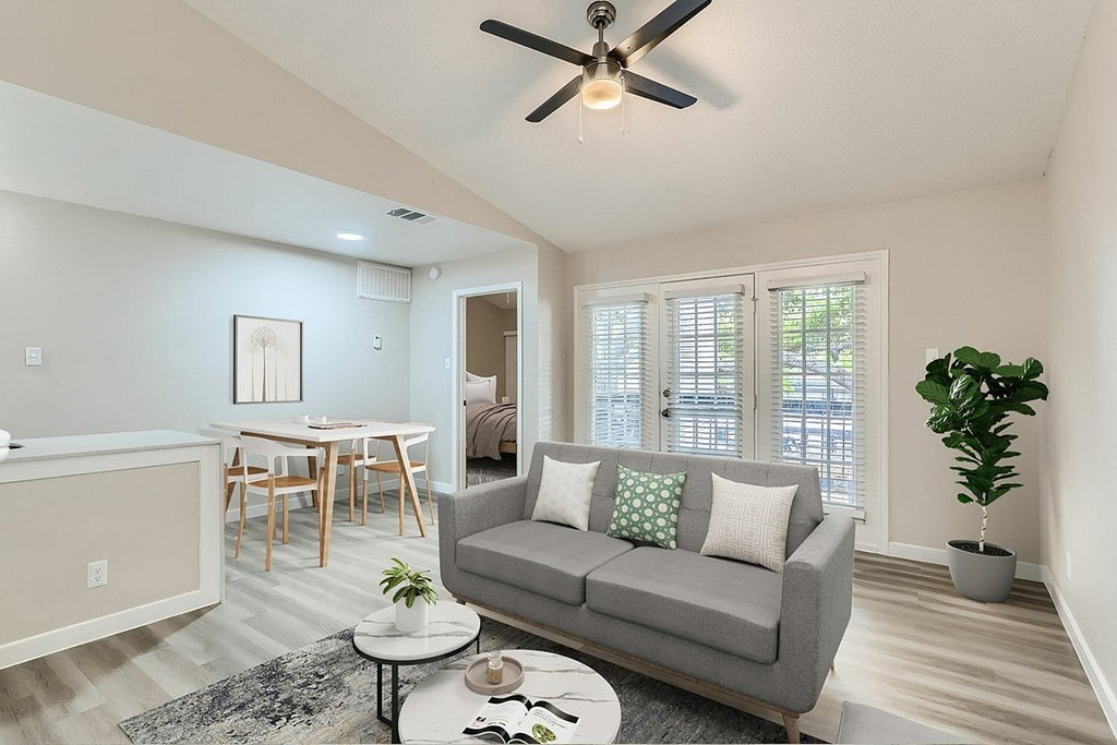 A living room with a grey couch, a coffee table, and a ceiling fan.