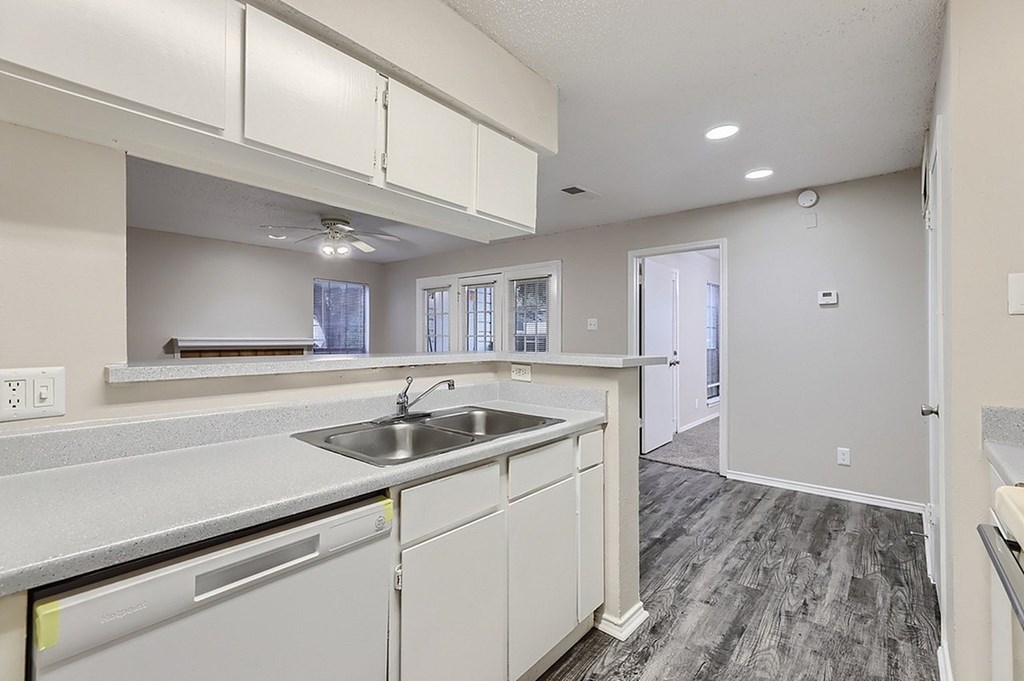 A kitchen with white cabinets and a grey floor.