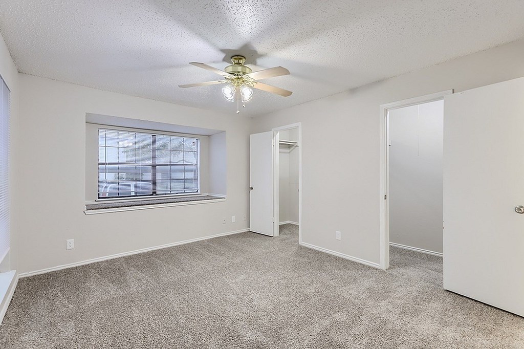 A room with a ceiling fan and carpeted floor.
