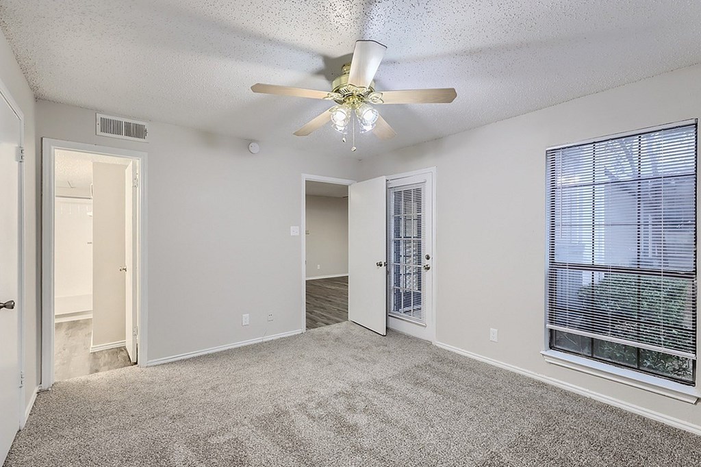 A room with a ceiling fan and carpeted floor.