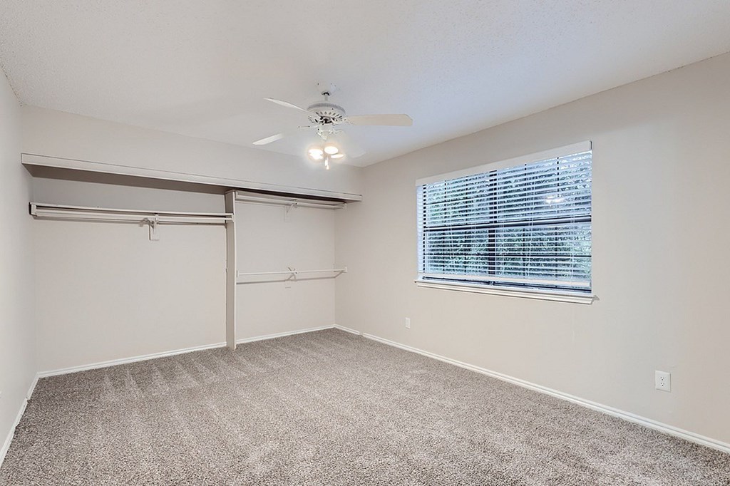 A room with a sliding door, carpeted floor, and a ceiling fan.