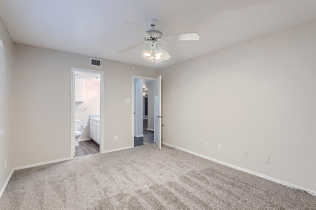 A spacious room with a ceiling fan and carpeted floor.