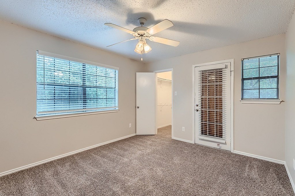 A room with a ceiling fan and two windows with blinds.