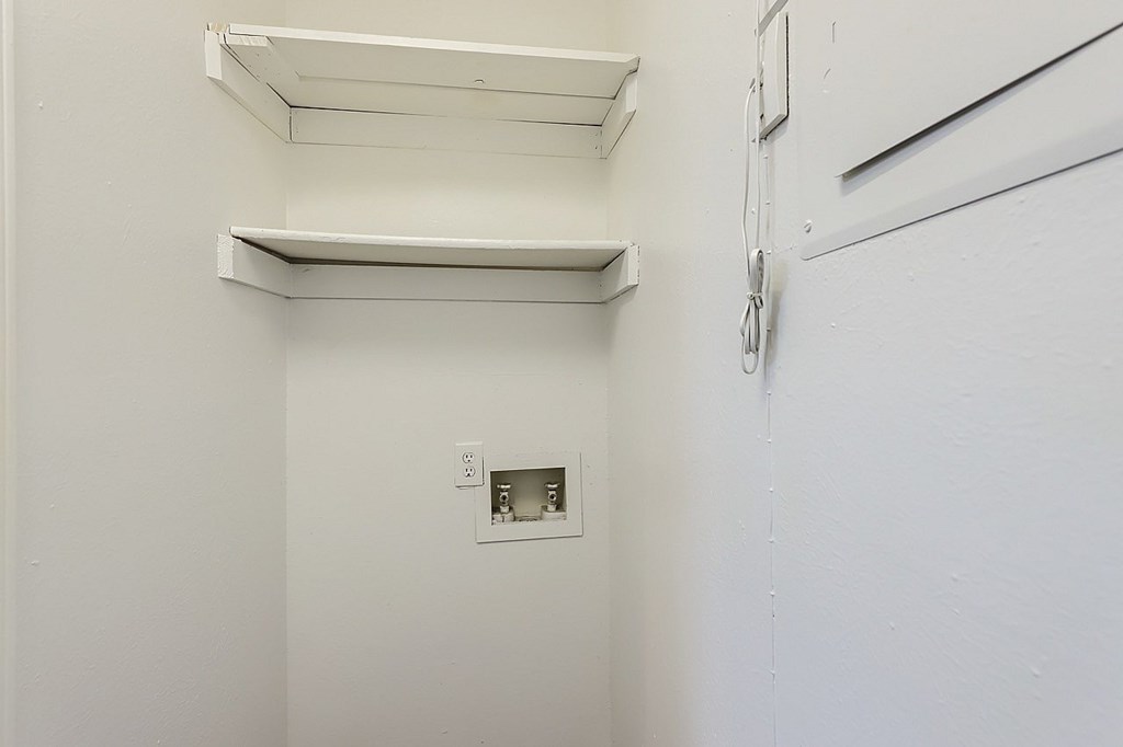 A white wall with a switch and a white shelf.