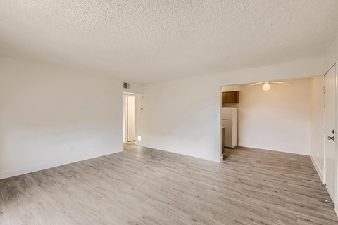 A spacious room with wooden flooring and white walls.