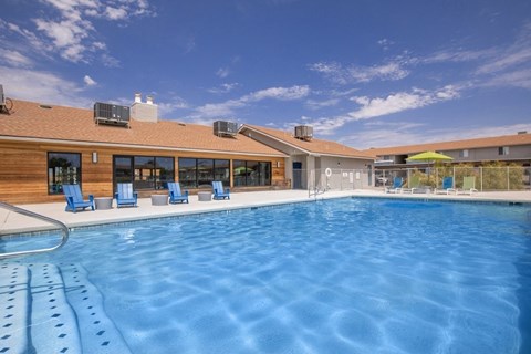 A large outdoor swimming pool with lounge chairs and a building in the background.