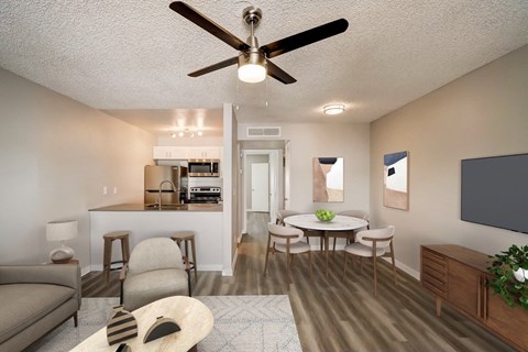 A living room with a couch, chairs, a table, and a ceiling fan.