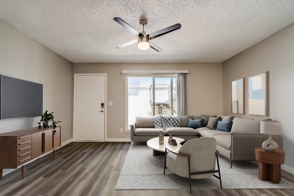 A living room with a grey sofa, a wooden cabinet, a ceiling fan, and a rug.