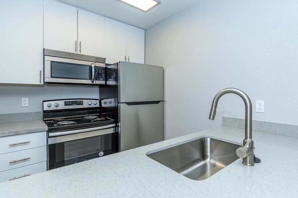 A kitchen with a stainless steel refrigerator, oven, and microwave.