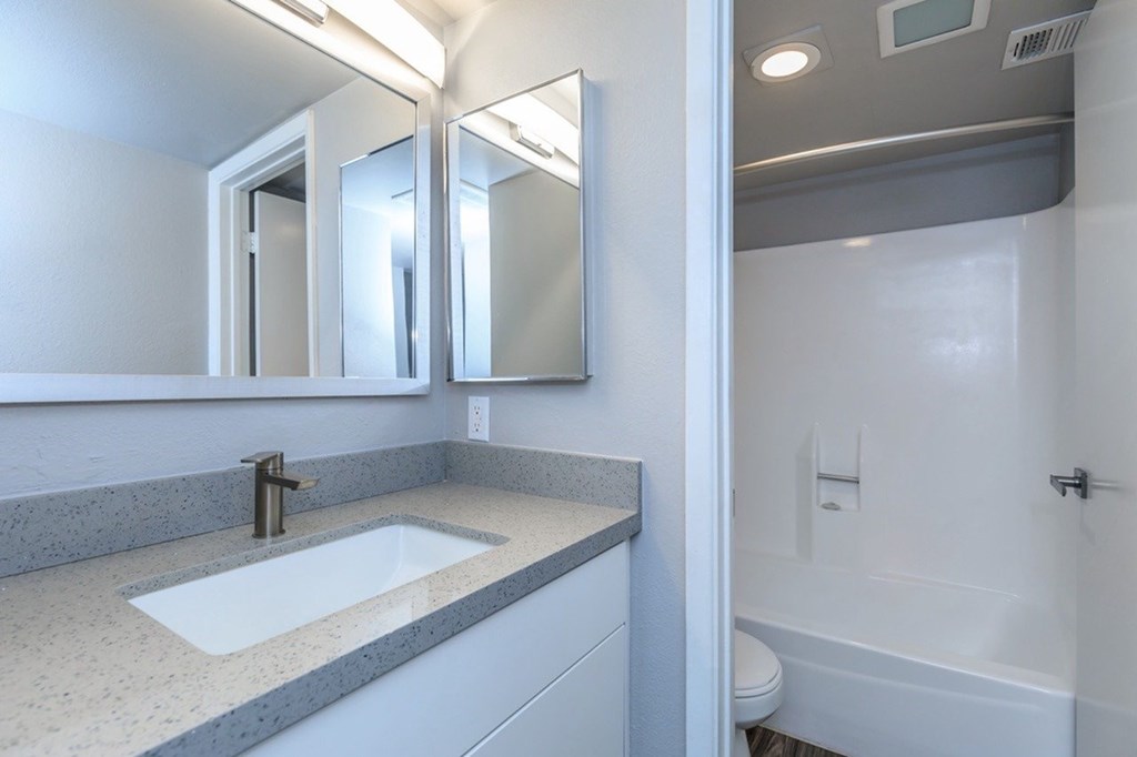 A bathroom with a sink, mirror, and bathtub.