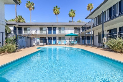 A swimming pool in front of a building with palm trees.