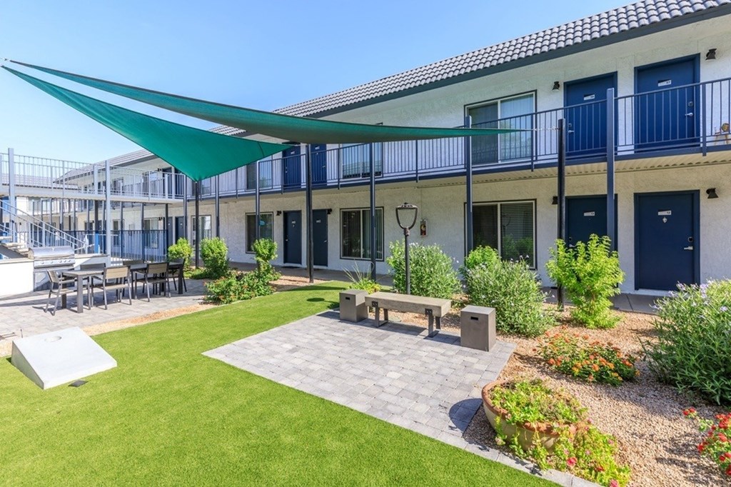 A patio area with a bench and a table under a green awning.