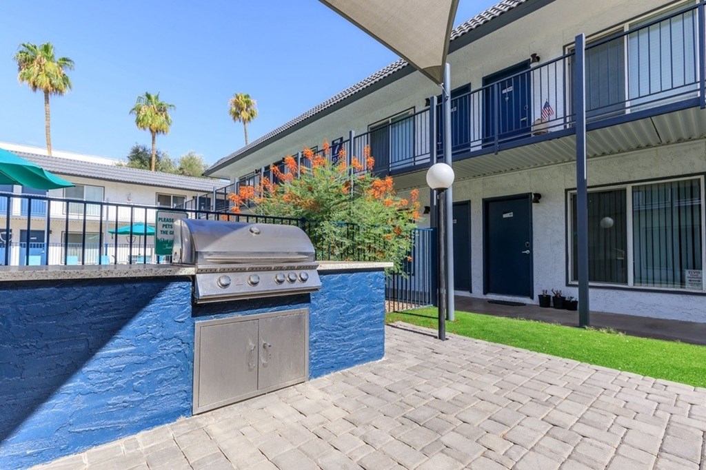 A blue pool with a grill next to a building with balconies.