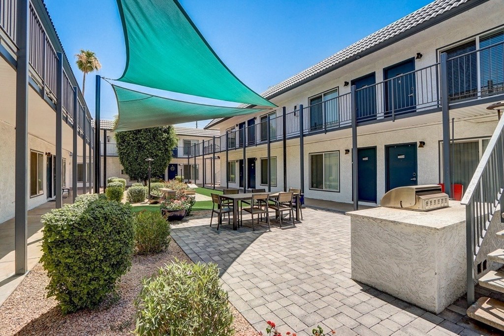 A patio with a table and chairs under a green shade sail.