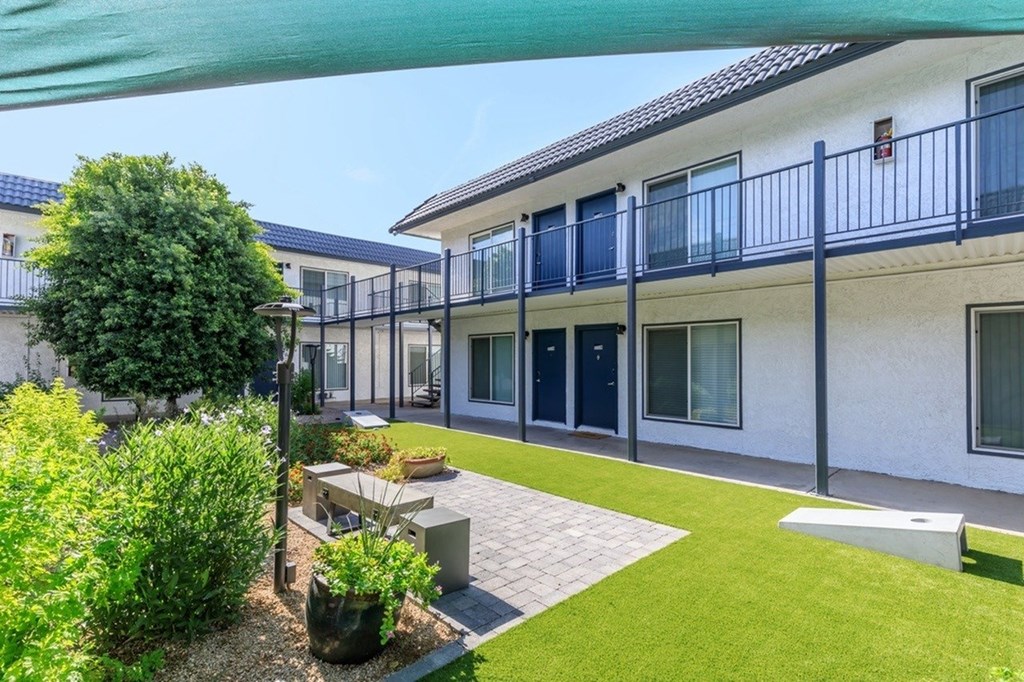 A white building with a balcony and a green lawn in front.