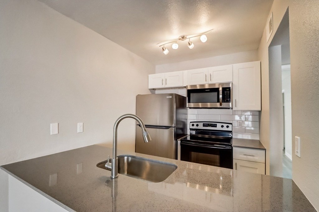 A kitchen with a sink, stove, and refrigerator.