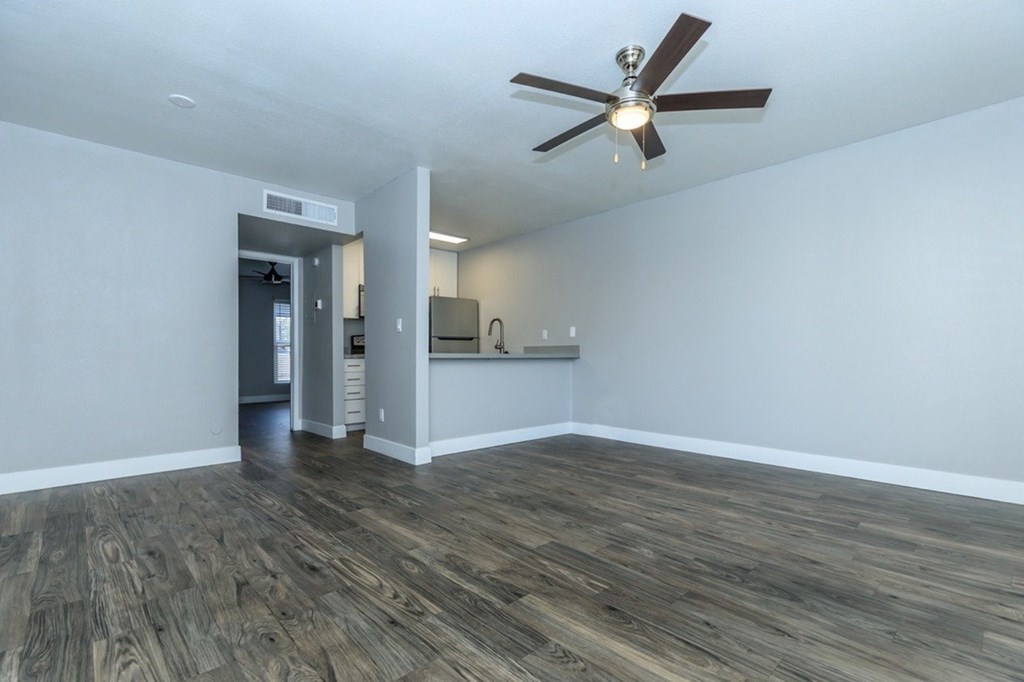A room with a ceiling fan and wood flooring.