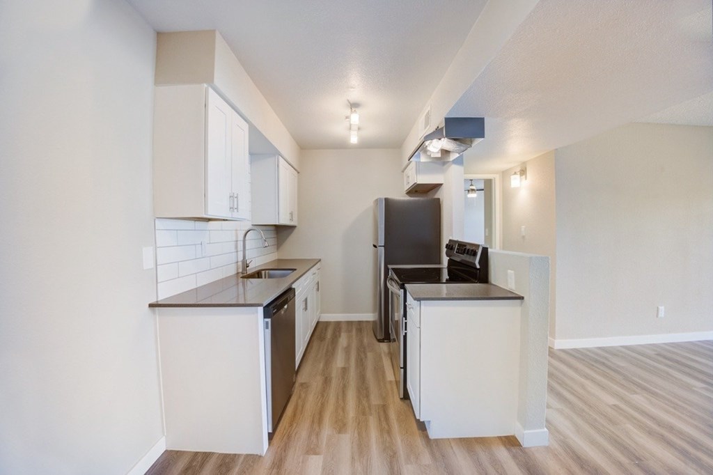 A kitchen with white cabinets and a black refrigerator.
