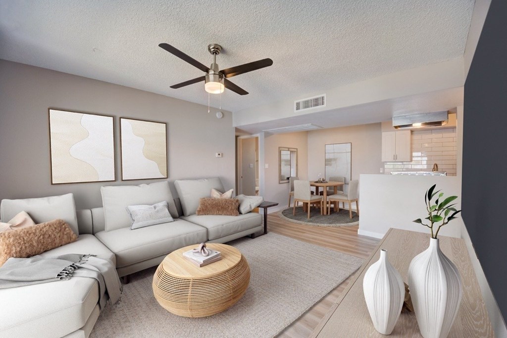 A living room with a white couch, a wooden coffee table, and a ceiling fan.
