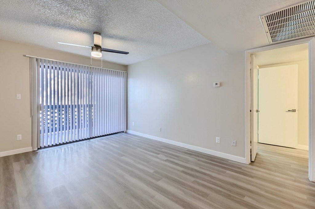 A room with a ceiling fan and sliding glass doors.