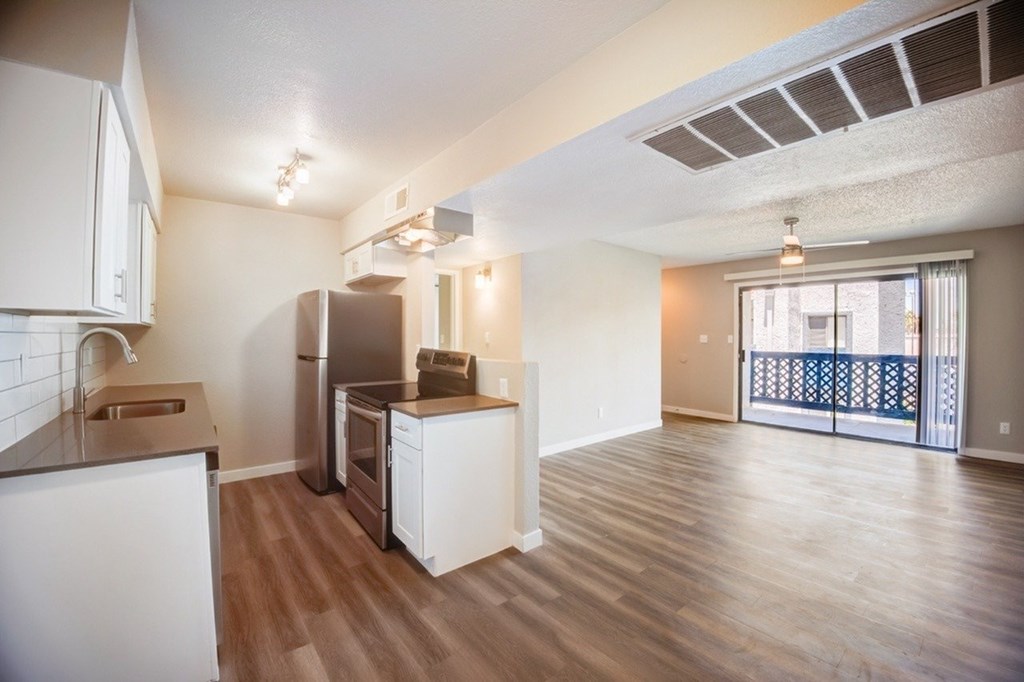 A kitchen with white appliances and wooden floors.