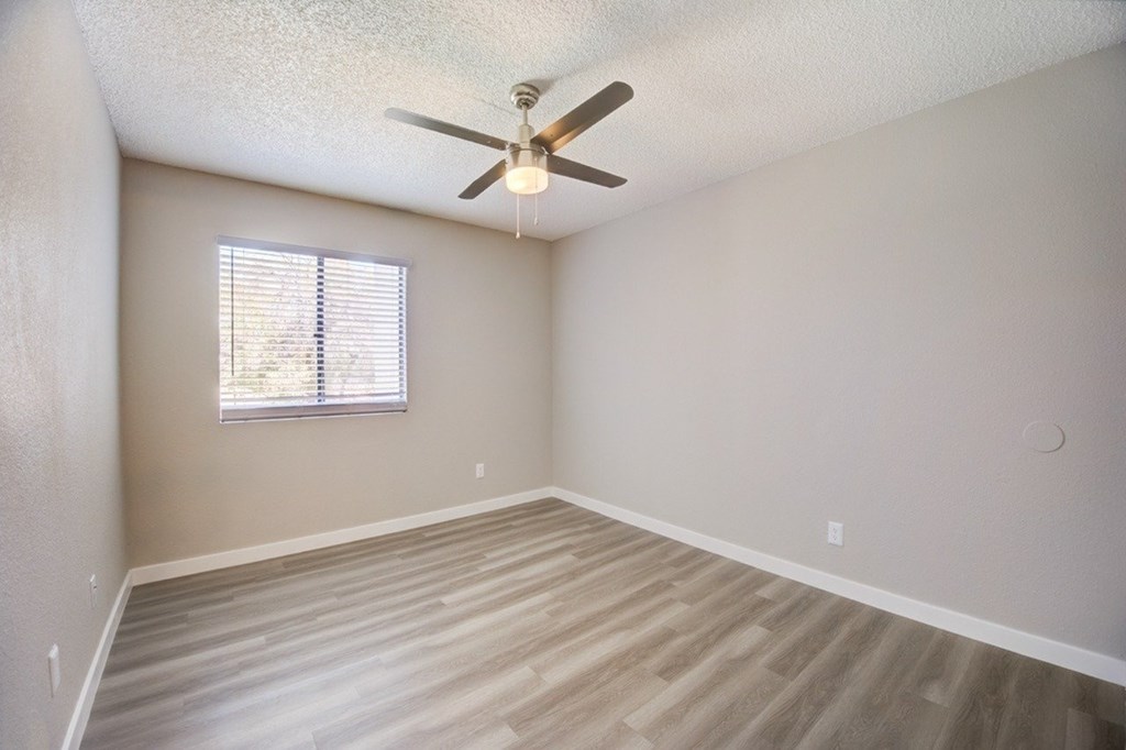 A room with a ceiling fan and a window with blinds.
