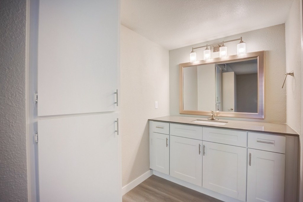 A bathroom with a sink, mirror, and cabinets.