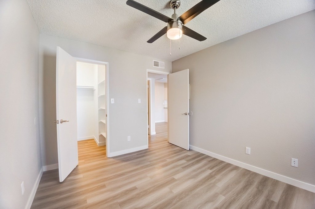 A room with a ceiling fan and light fixture, and a wooden floor.