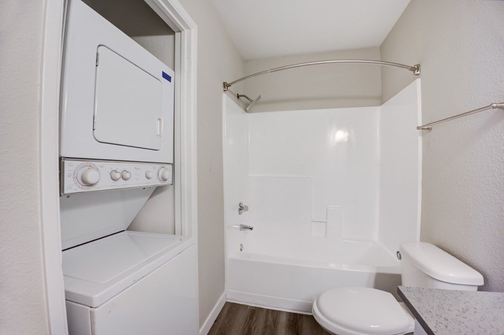 A small white bathroom with a toilet, a bathtub, and a small oven.