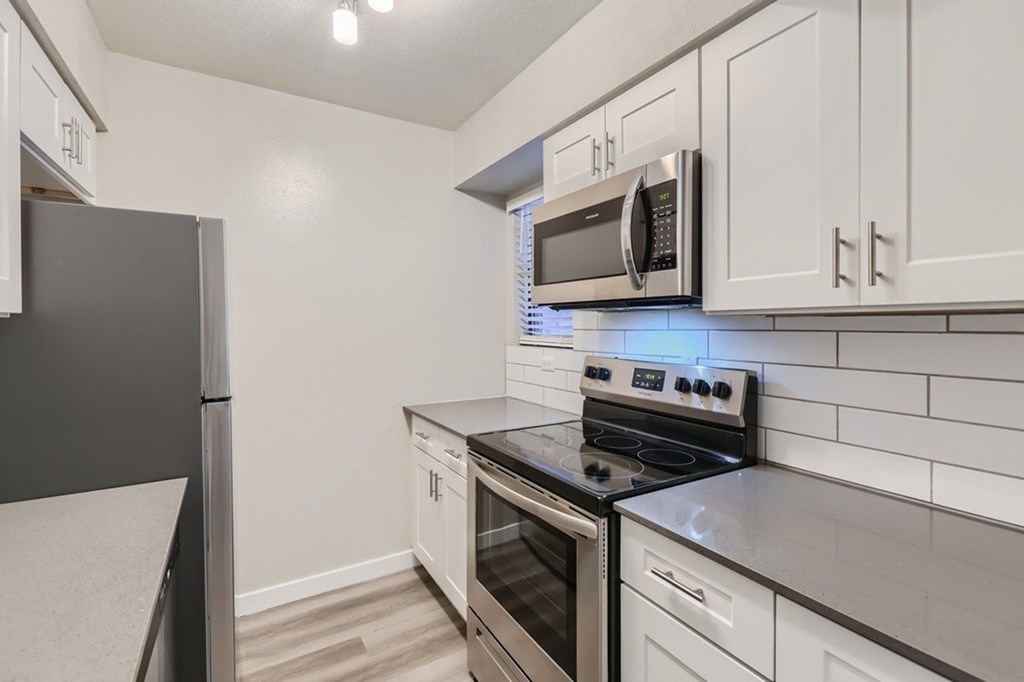 A kitchen with a black refrigerator and a black stove top oven.