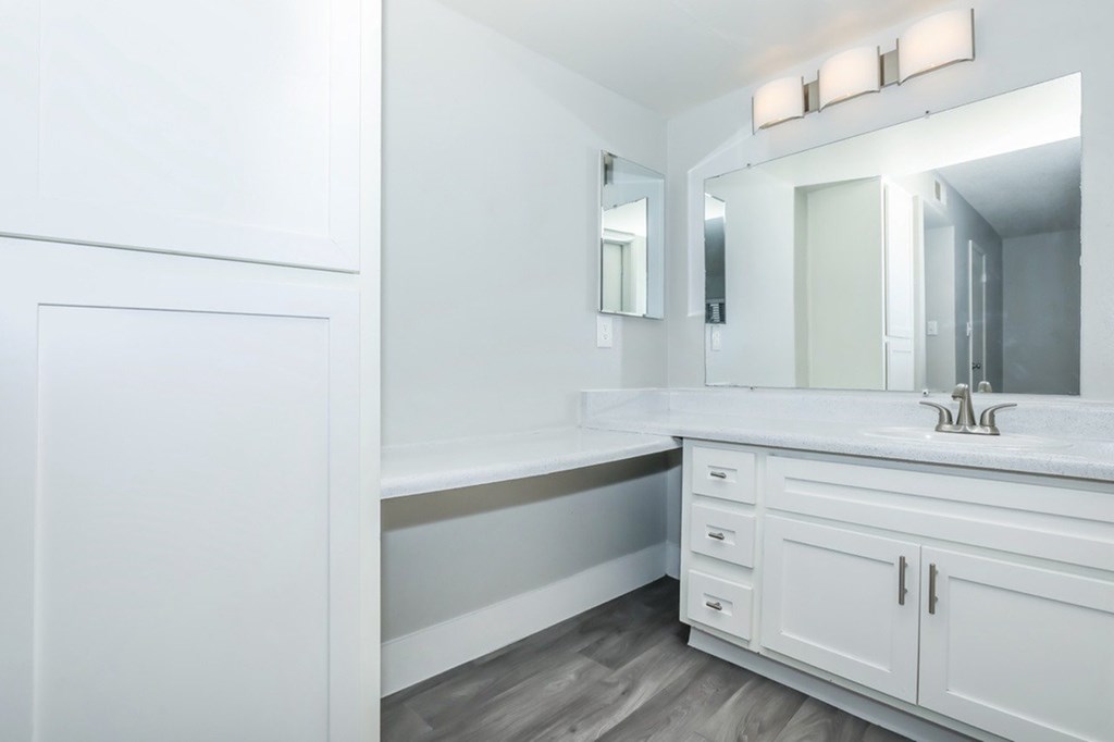 A white bathroom with a vanity and a large mirror.