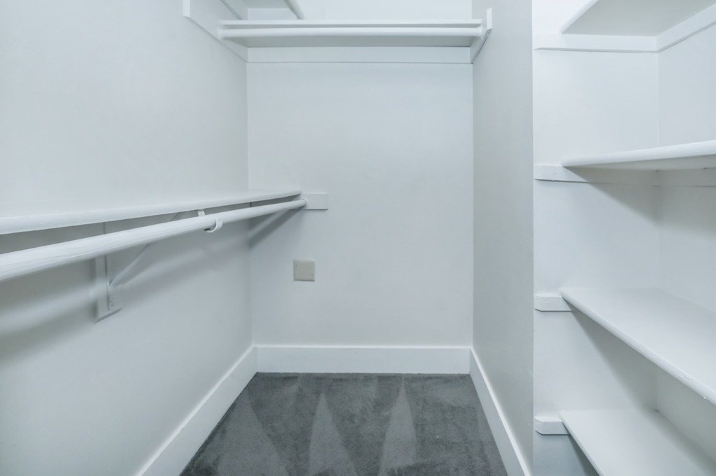 A white pantry with a grey floor and white shelves.