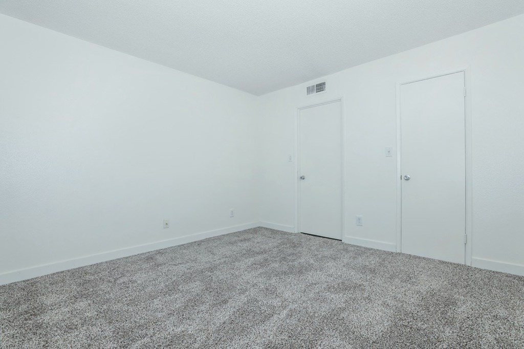 A room with white walls and grey carpet.