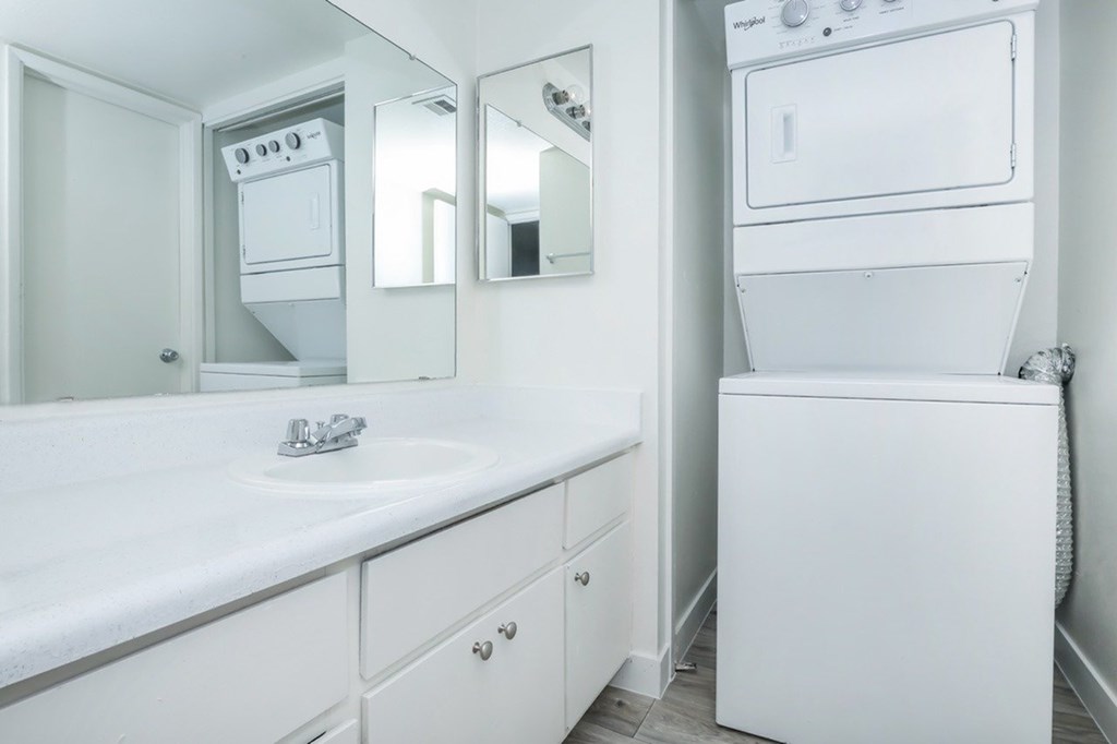A white bathroom with a sink, mirror, and a white oven.