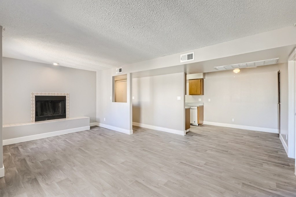 A spacious living room with a fireplace and wood flooring.