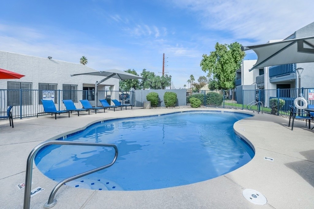 A large outdoor swimming pool with a metal ladder and a metal fence.