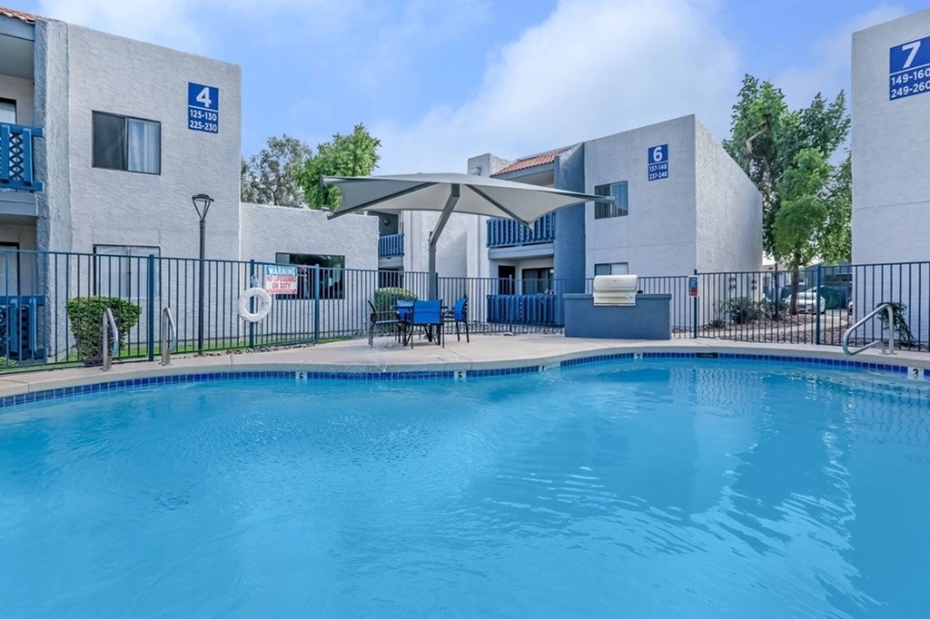 A swimming pool is in front of a building with a blue sign.
